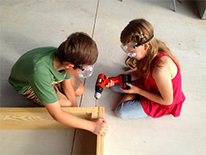 Two children doing a hands-on project (building a shelf using power tools)